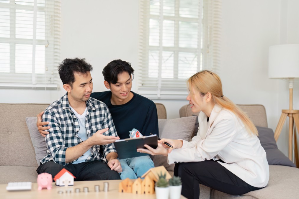 Trois colocataires discutant de la répartition de leur budget et de leur contrat d'assurance habitation étudiant dans leur salon.
