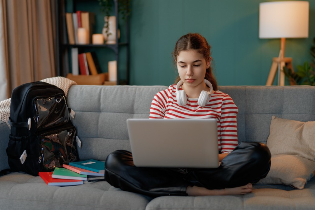Étudiante travaillant sur son ordinateur portable dans le salon de son appartement, un équipement de valeur protégé par l'assurance habitation étudiant.